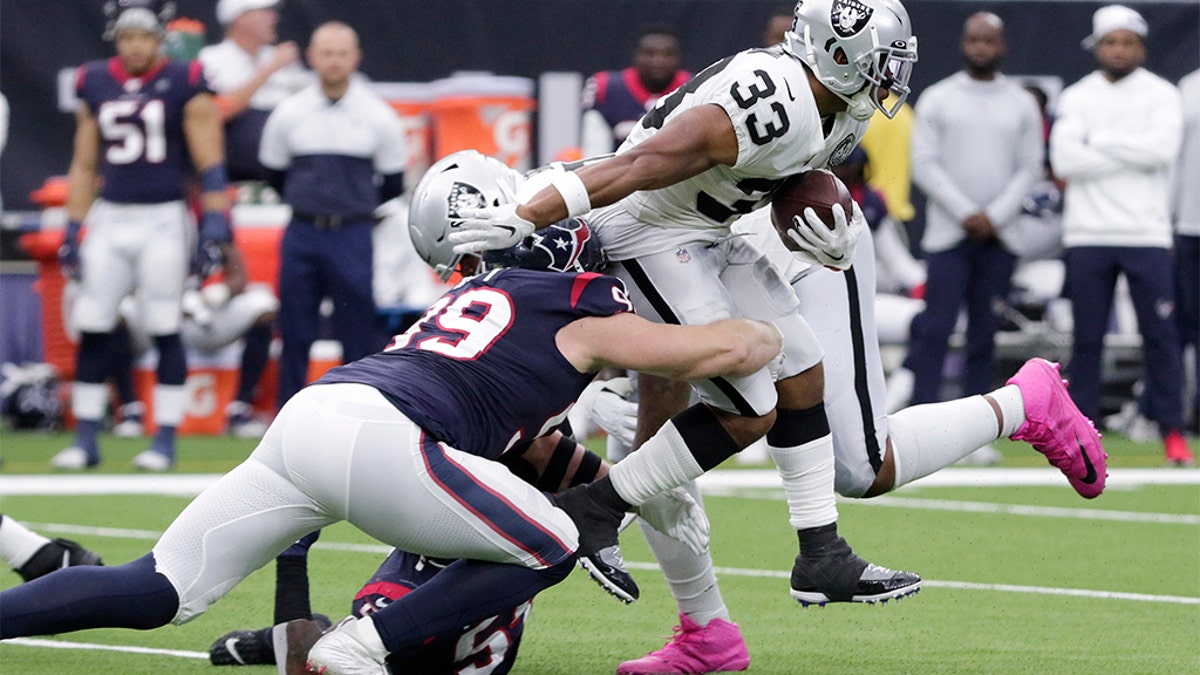 Oakland Raiders running back DeAndre Washington (33) is hit by Houston Texans defensive end J.J. Watt (99) on a run during the first half of an NFL football game Sunday, Oct. 27, 2019, in Houston. (AP Photo/Michael Wyke)