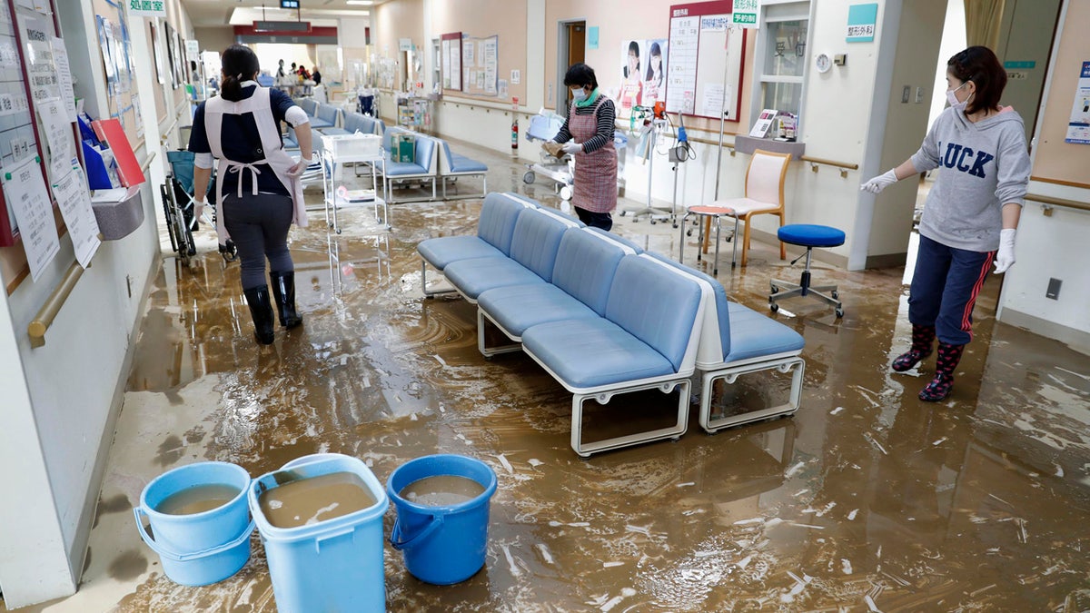 Staff members clean a hospital damaged by Typhoon Hagibis, in Marumori town, Miyagi prefecture, Japan Tuesday, Oct. 15, 2019.