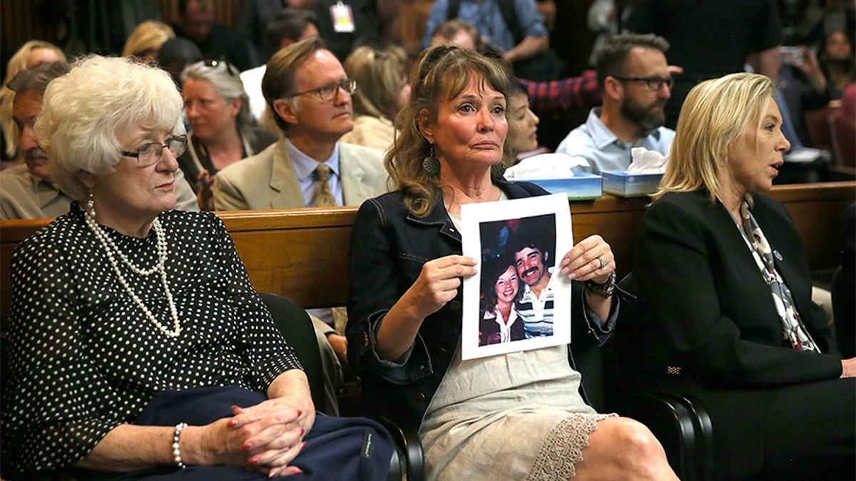 An attendee holds a photo of Cheri Domingo and her boyfriend Gregory Sanchez, who were killed in 1981, during DeAngelo's arraignment.
