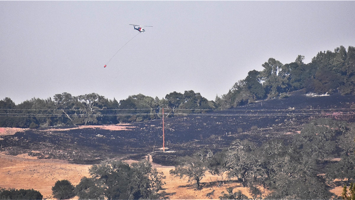 Helicopters drop water on hilltops as soldiers from the 49th Military Police Brigade operate traffic control points. (California National Guard)