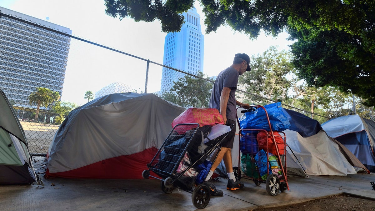 A homeless man moves his belongings from a street behind Los Angeles City Hall as crews prepared to clean the area on July 1, 2019.