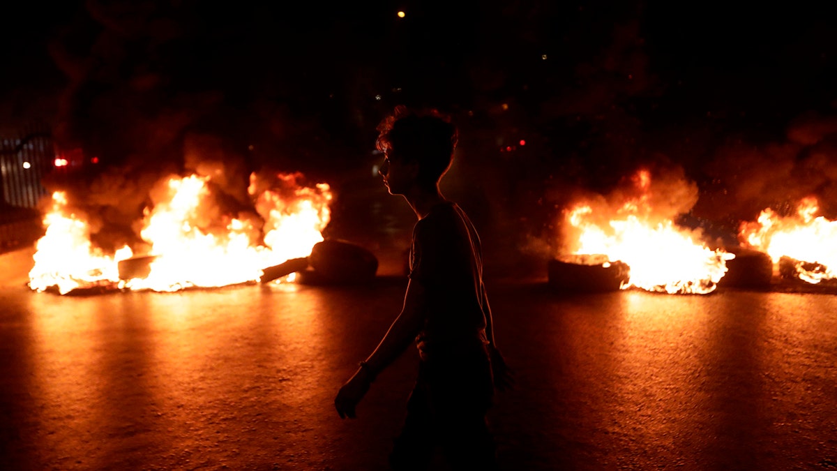 A Lebanese demonstrator walks past burning tires during the tax protest in a Beirut suburb.  (Anwar Amro/AFP via Getty Images)