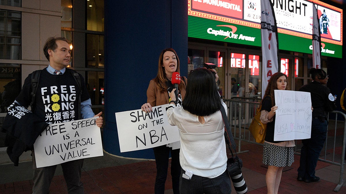 Activists hold signs outside Capital One Arena before an NBA preseason basketball game between the Washington Wizards and the Guangzhou Loong-Lions, Wednesday, Oct. 9, 2019, in Washington. (AP Photo/Nick Wass)