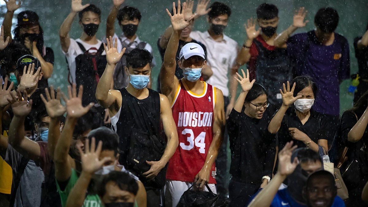 A demonstrator wearing Houston Rockets jersey holds up his hand with fellow demonstrators during a rally at the Southorn Playground in Hong Kong, Tuesday, Oct. 15, 2019. (AP Photo/Mark Schiefelbein)