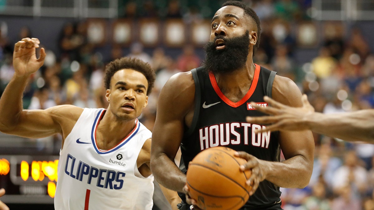 Houston Rockets shooting guard James Harden (13) gets by Los Angeles Clippers shooting guard Jerome Robinson (1) during the first quarter of an NBA preseason basketball game, Thursday, Oct 3, 2019, in Honolulu. (AP Photo/Marco Garcia)