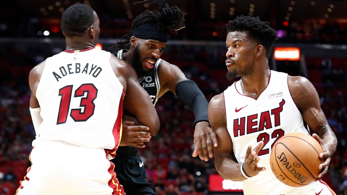 Miami Heat forward Jimmy Butler (22) dribbles the ball against San Antonio Spurs forward DeMarre Carroll (77) during the second half of an NBA preseason basketball game Tuesday, Oct. 8, 2019, in Miami. (AP Photo/Brynn Anderson)