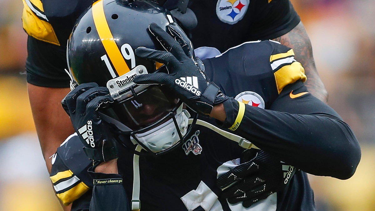 Pittsburgh Steelers running back James Conner (30) holds onto wide receiver JuJu Smith-Schuster (19) who reacts after quarterback Mason Rudolph (2) was injured in the second half of an NFL football game against the Baltimore Ravens, Sunday, Oct. 6, 2019, in Pittsburgh. (AP Photo/Don Wright)