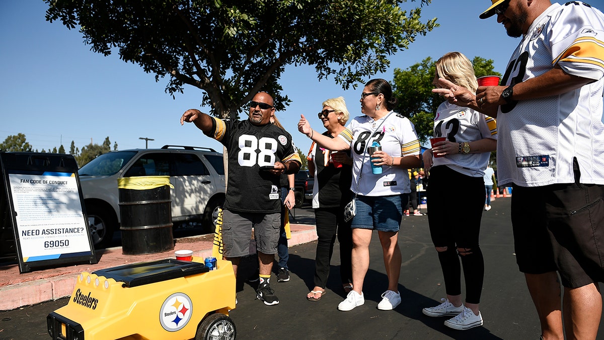 Fans stand in front of a remote controlled cooler prior to an NFL football game between the Pittsburgh Steelers and the Los Angeles Chargers, Sunday, Oct. 13, 2019, in Carson, Calif. (AP Photo/Kelvin Kuo)