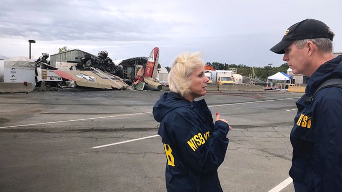 In this photo released via Twitter by the National Transportation Safety Board, NTSB board Member Jennifer Homendy, left, and investigator Dan Bower stand at the scene where a World War II-era bomber plane, left, crashed at Bradley International Airport in Windsor Locks, Conn., Wednesday, Oct. 2, 2019.