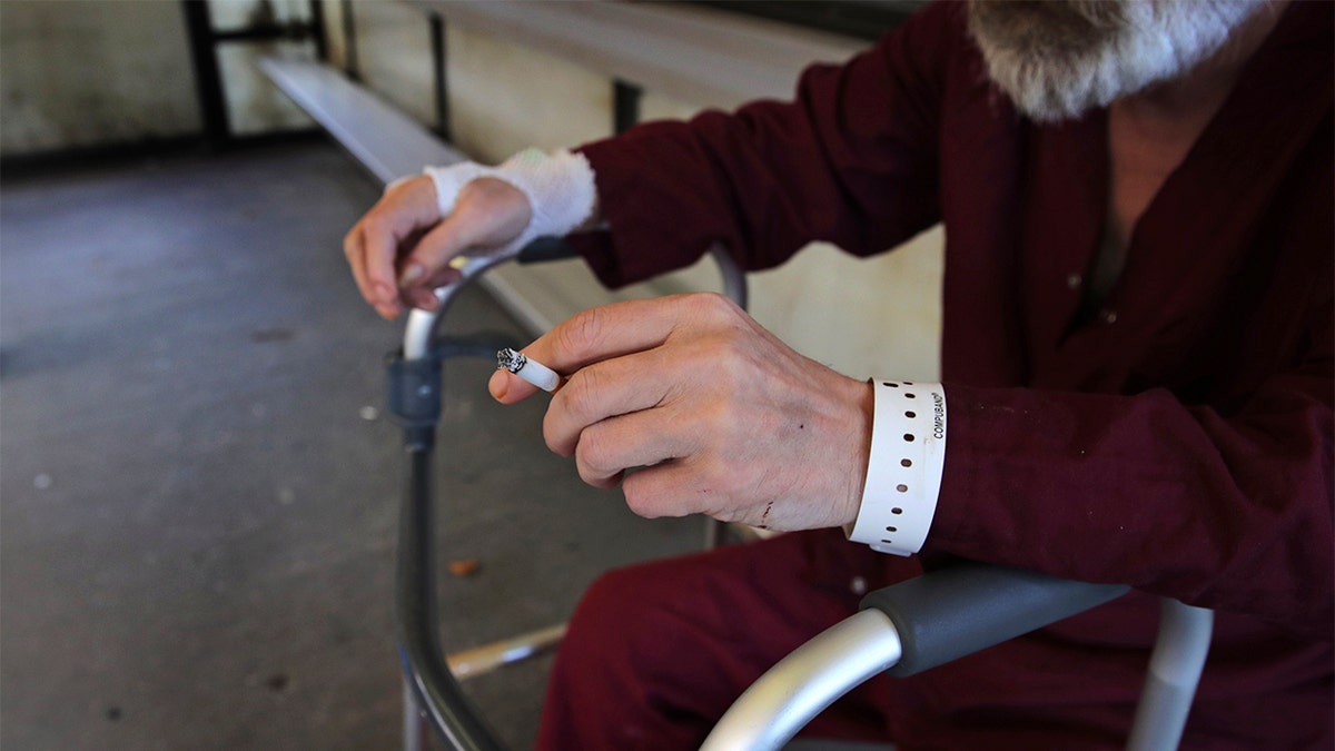 Patient Michael Swan rests his arm on his walker while taking a cigarette break in the smoking shack outside the West Roxbury campus of the Veterans Affairs Medical Center in Boston, Monday, Sept. 30, 2019. The VA is set to ban smoking at all its grounds nationwide starting Oct. 1, a welcome move by health-conscious veterans but not by others who enjoy a smoke between appointments. (AP Photo/Charles Krupa)