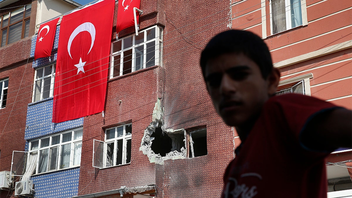 A child stands across from a building damaged by a mortar fired from inside Syra, in Akcakale, Sanliurfa province, southeastern Turkey, Sunday, Oct. 13, 2019. Incoming shells fired from northeastern Syria hit the house earlier on Sunday. Two residents were at the house and were evacuated. (AP Photo/Lefteris Pitarakis)