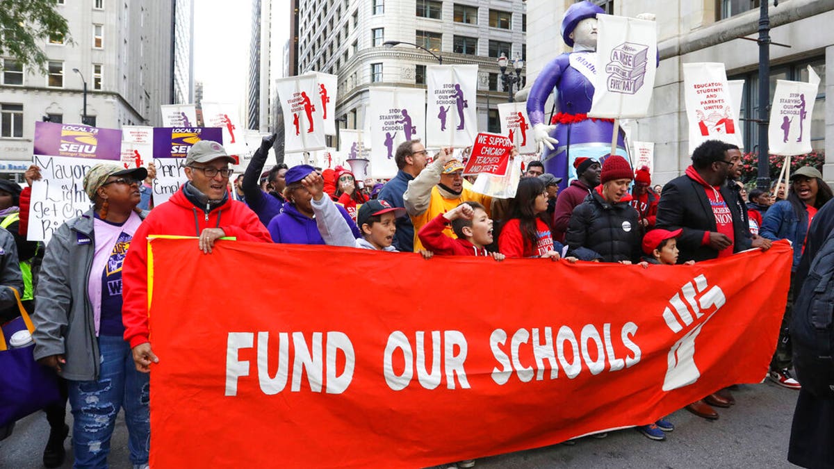 Teachers, staff and their supporters march through downtown Chicago, Monday, Oct. 14, 2019. (AP Photo/Teresa Crawford)