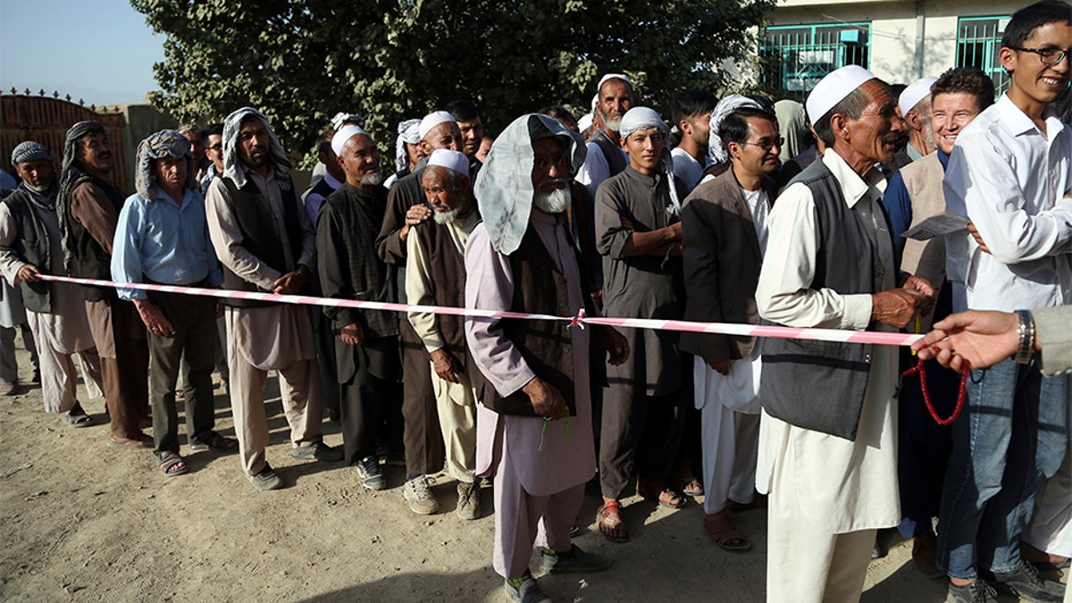 Men line up outside a polling station in western neighborhood of Kabul, Afghanistan, on Saturday. Afghans headed to the polls that day to elect a new president amid high security and threats of violence from Taliban militants, who warned citizens to stay away from polling stations or risk being hurt.