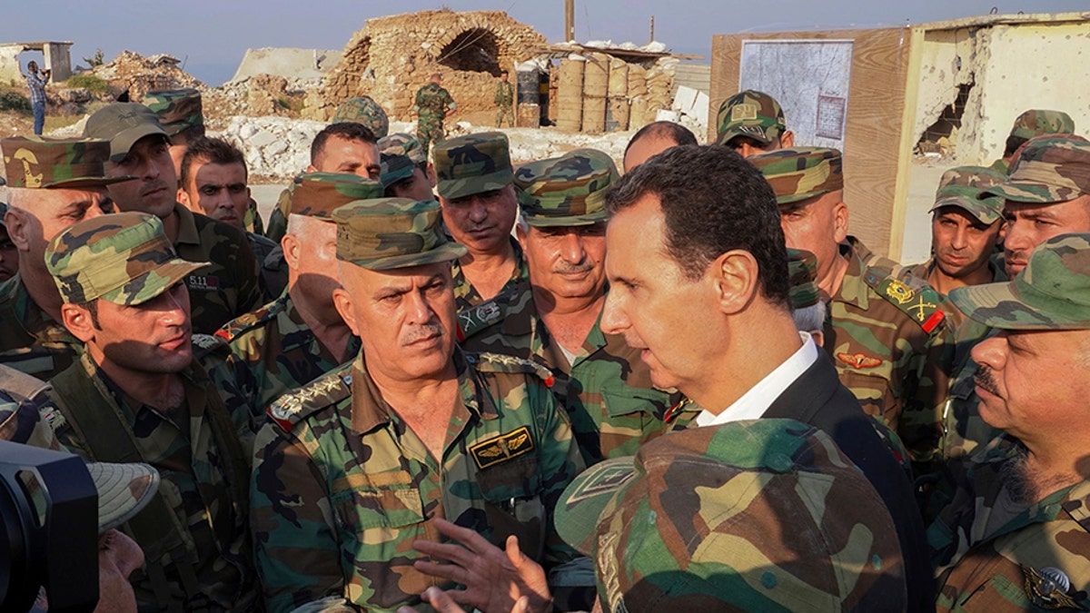 In this photo released on the official Facebook page of the Syrian Presidency, Syrian President Bashar Assad, center right, speaks with Syrian troops during his visit to the town of Habeet, in the northwestern province of Idlib, Syria, on Tuesday.