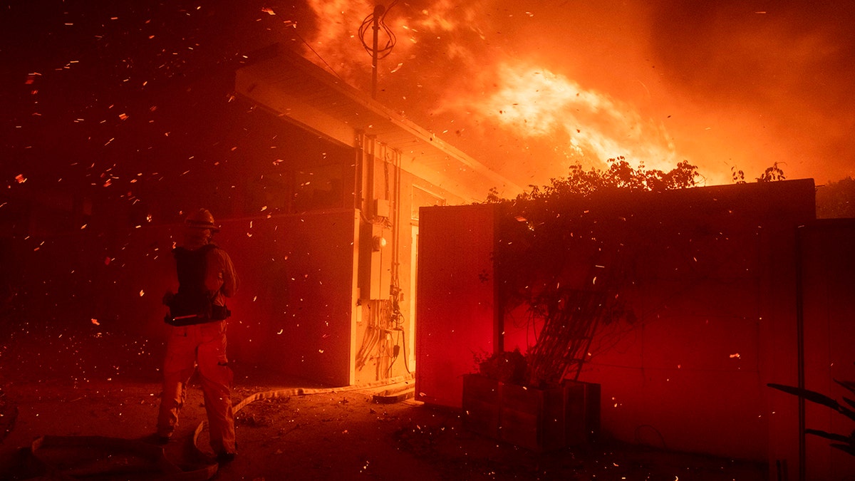 Firefighters try to save a home from a wildfire on Tigertail Road Monday, Oct. 28, 2019, in Los Angeles, Calif.