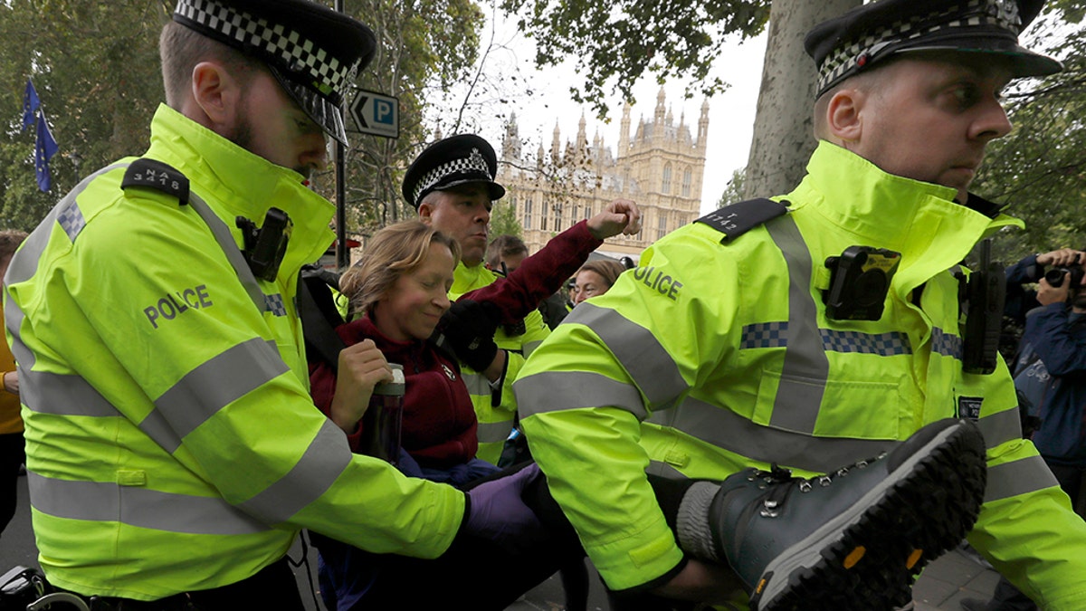 A demonstrator is arrested by police officers during in a climate protest near Parliament in London, Tuesday, Oct. 8, 2019. Police are reporting they have arrested more than 300 people at the start of two weeks of protests as the Extinction Rebellion group attempts to draw attention to global warming. (AP Photo/Kirsty Wigglesworth)