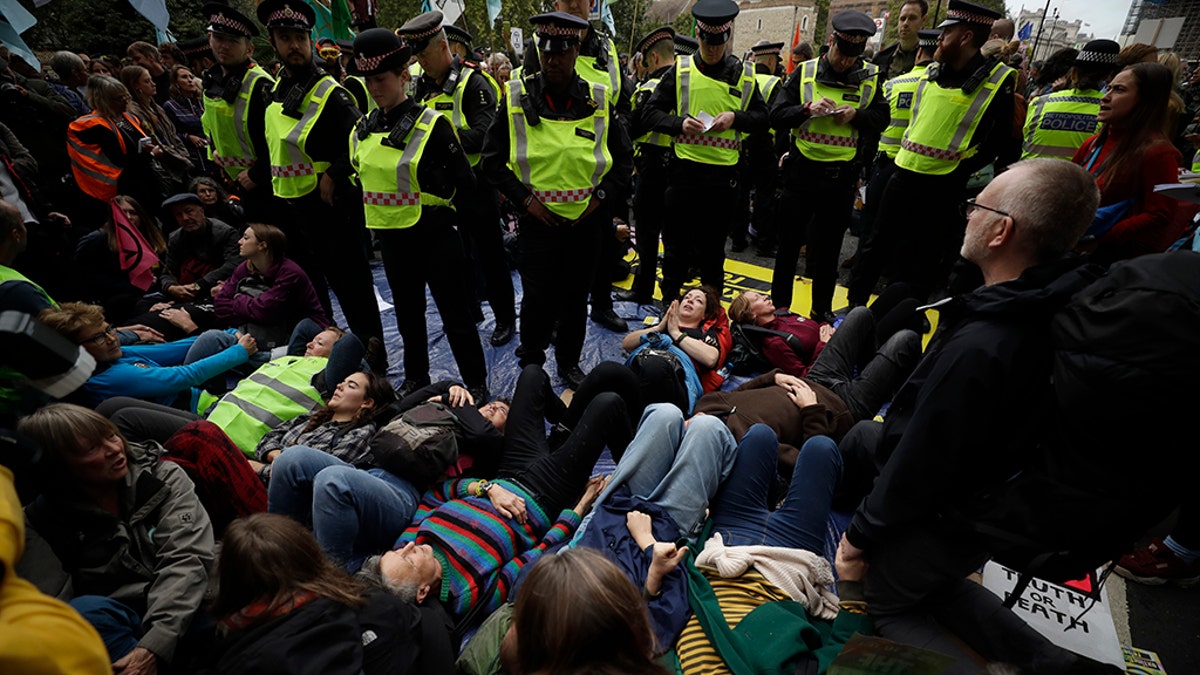 Extinction Rebellion climate change protesters lie down and block the street on Millbank in London, Tuesday, Oct. 8, 2019. Hundreds of climate change activists camped out in central London on Tuesday during a second day of world protests by the Extinction Rebellion movement to demand more urgent actions to counter global warming. (AP Photo/Matt Dunham)
