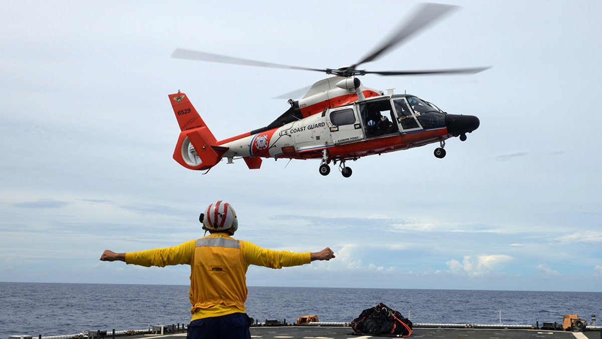 Coast Guard Cutter Munro crew members conduct flight operations with an Air Station Barbers Point HM-65 Dolphin helicopter aircrew from the flight deck on the Munro in the Central Pacific, in December 2018.