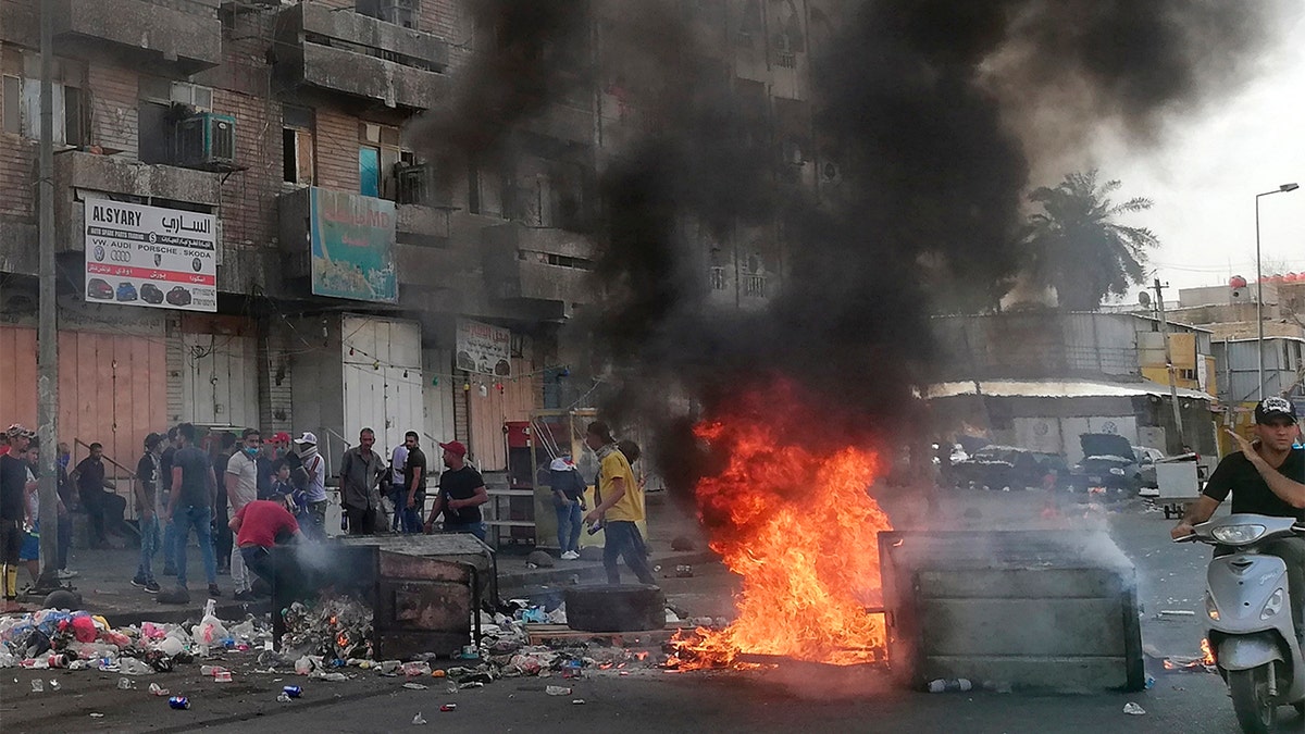 Antigovernment protesters set a fire and block roads in Baghdad on Wednesday. (AP Photo/Hadi Mizban)
