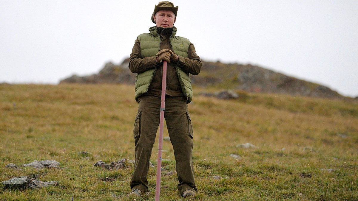 Putin poses with his walking stick on a hill in the Siberian mountains. (Alexei Druzhinin, Sputnik, Kremlin Pool Photo via AP)