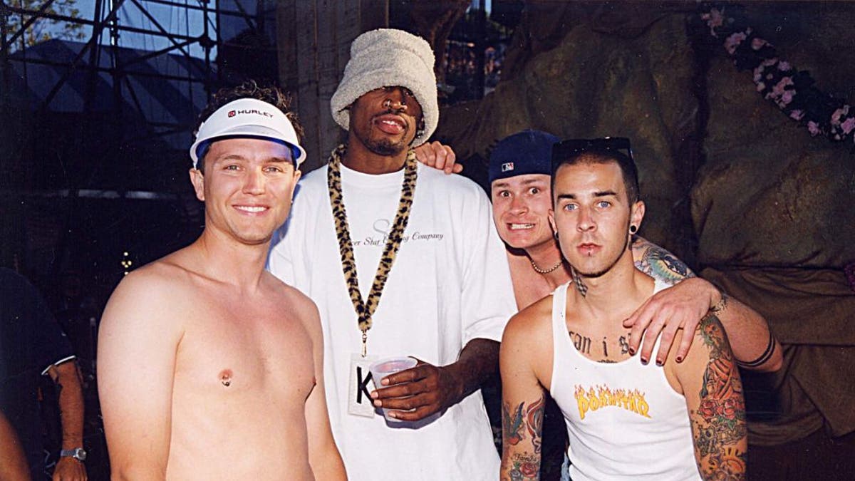 (L to R): Mark Hoppus, Dennis Rodman, Tom DeLonge and Travis Barker at the KROQ Weenie Roast in 1999. (Photo by Jeff Kravitz/FilmMagic, Inc)