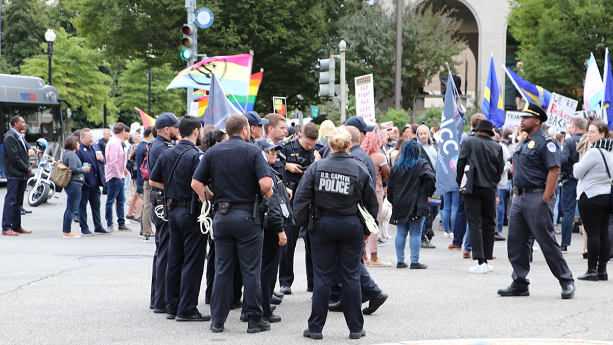 Police officers watch as protesters demonstrate about a block from the Supreme Court Tuesday morning after a report of suspicious packages moved the event from the Supreme Court steps. Capitol Police later said there was not a threat and the incident was cleared.