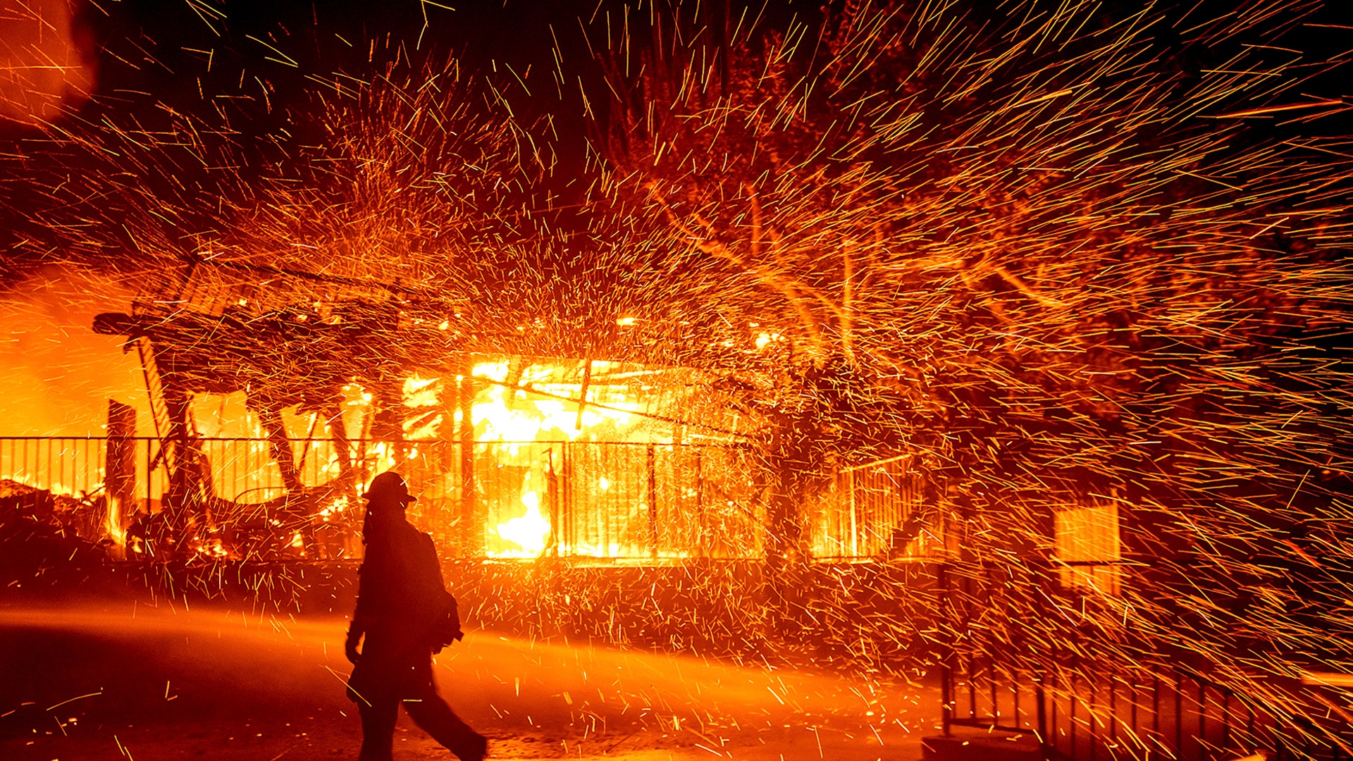 A firefighter passes a burning home as the Hillside fire burns in San Bernardino, Calif., Oct. 31, 2019. 