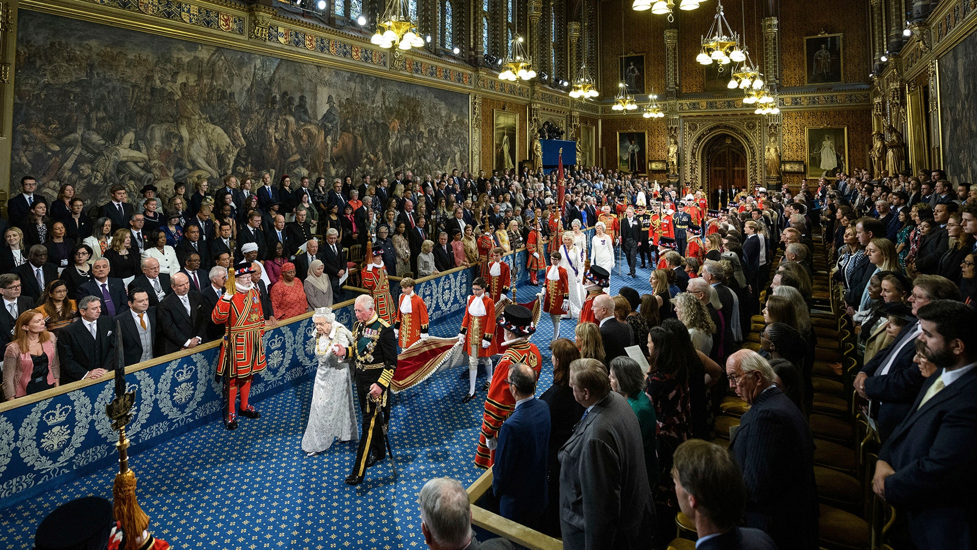 Britain's Queen Elizabeth II, accompanied by Prince Charles, proceed through the Royal Gallery before delivering the Queen's Speech during the State Opening of Parliament in London, Oct. 14, 2019. 