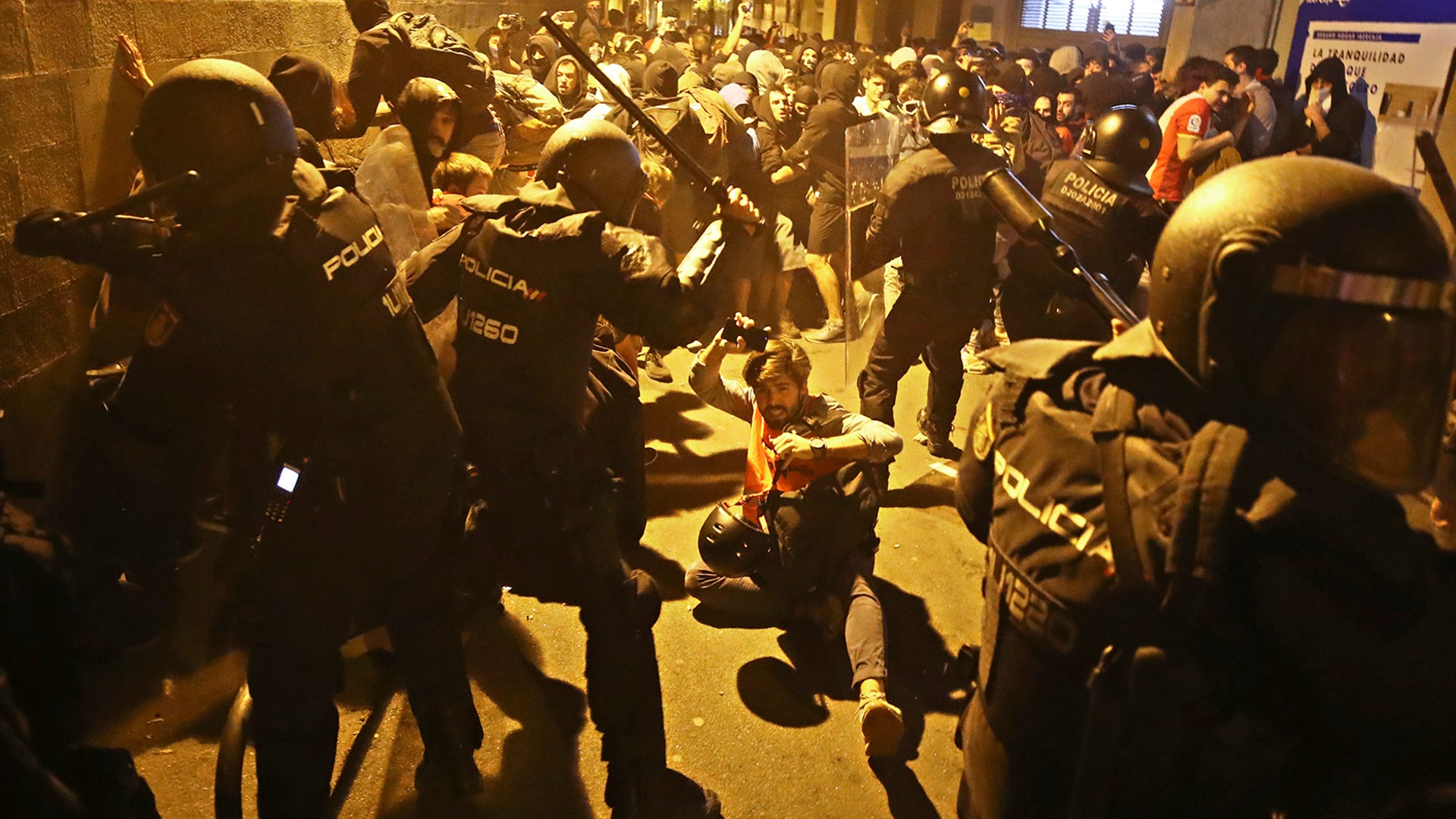 A journalist falls to the ground during clashes between protestors and police in Barcelona, Spain, Oct. 15, 2019. 