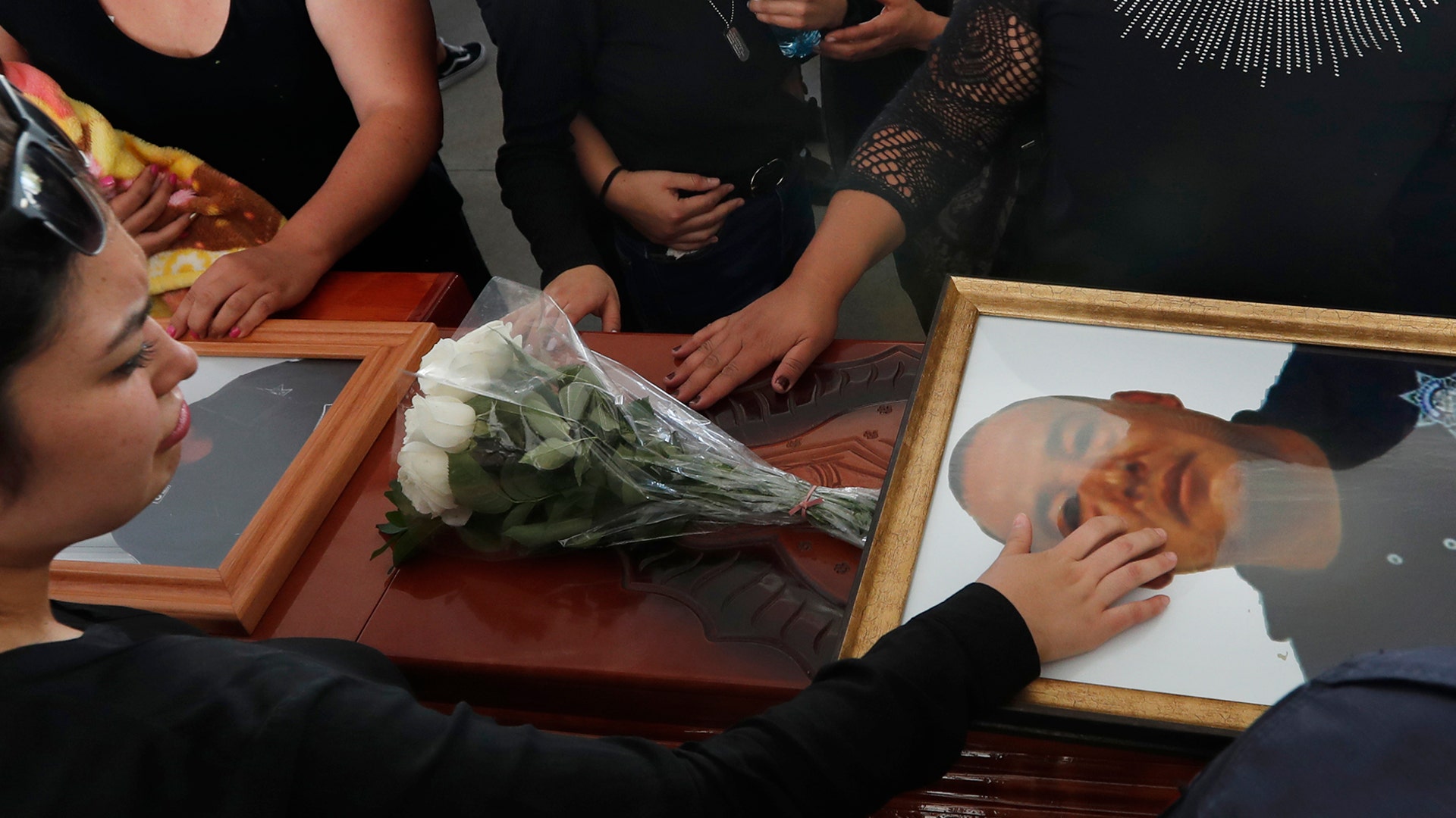 Relatives touch the coffin and photo of police officer Pablo Sergio Reynel, one of a group of officers killed in the line of duty, during a memorial service at the public security department headquarters for Michoacan, in Morelia, Mexico, Oct. 15, 2019. 