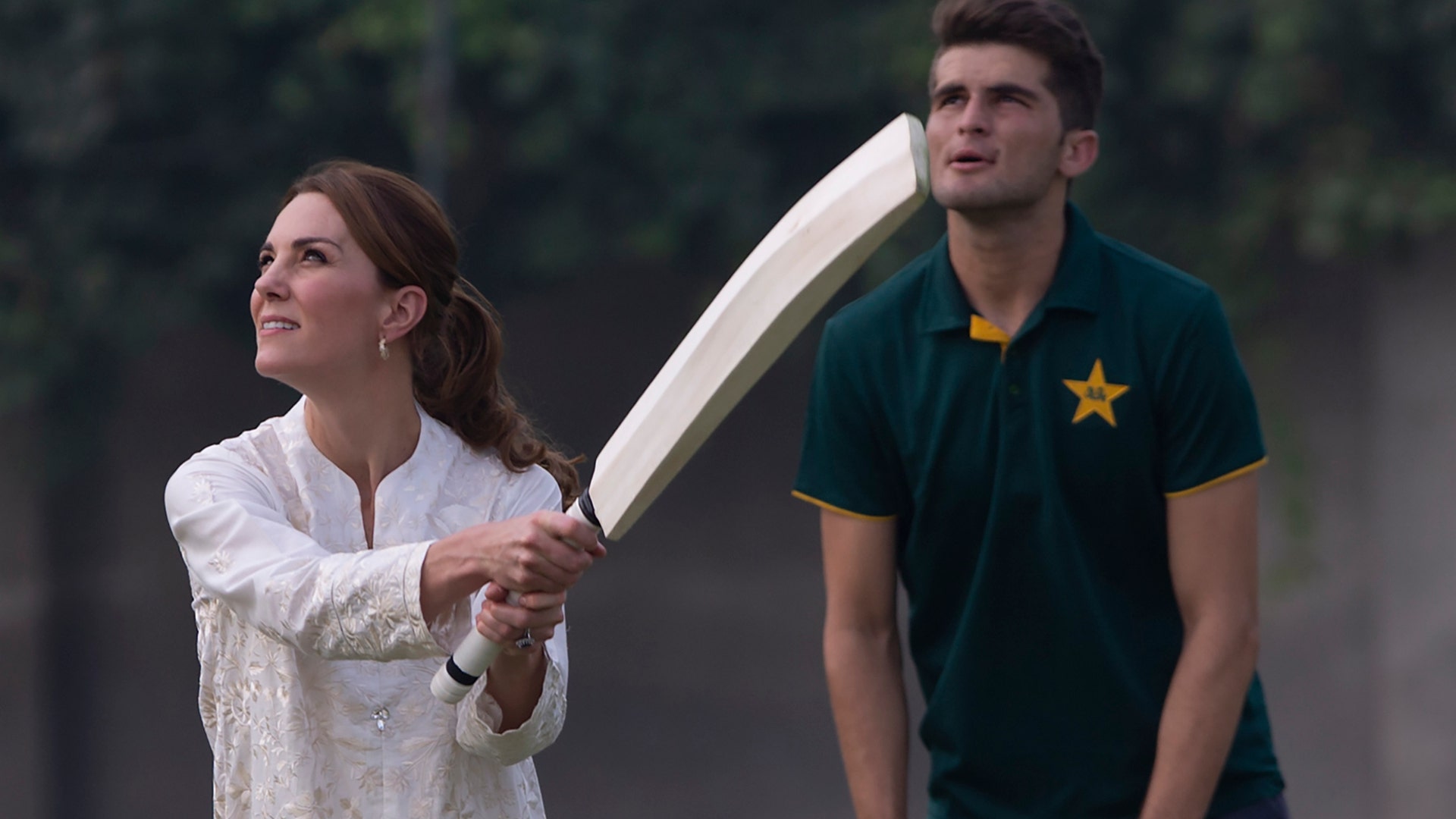 Britain's Kate, Duchess of Cambridge bats as Pakistani cricketer Shaheen Afridi looks on during her visit to the Pakistan Cricket Academy in Lahore, Pakistan, Oct. 17, 2019. 