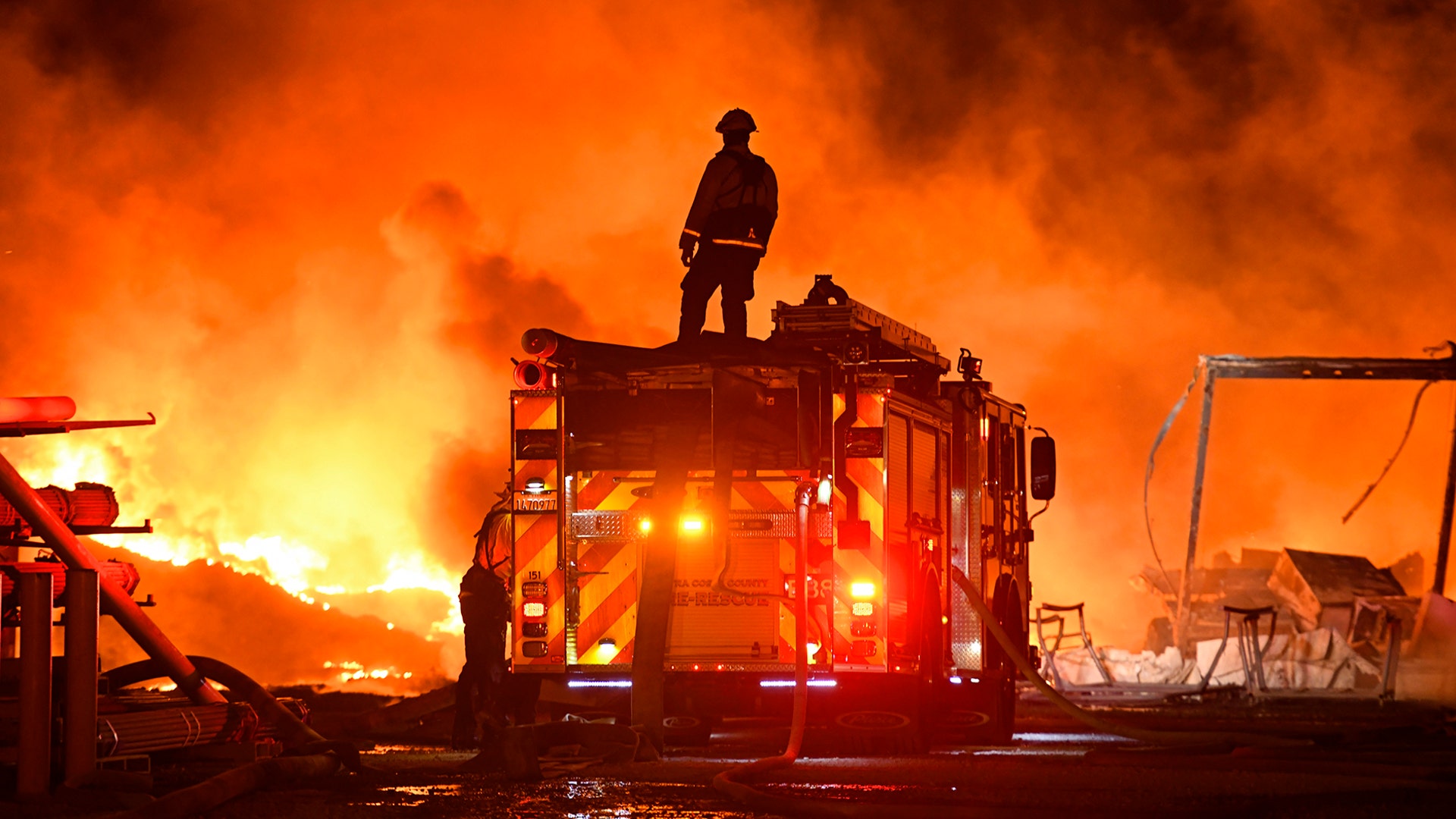 A firefighter stops to look at a wall of fire while battling a grass fire in Knightsen, California, Oct. 27, 2019. 
