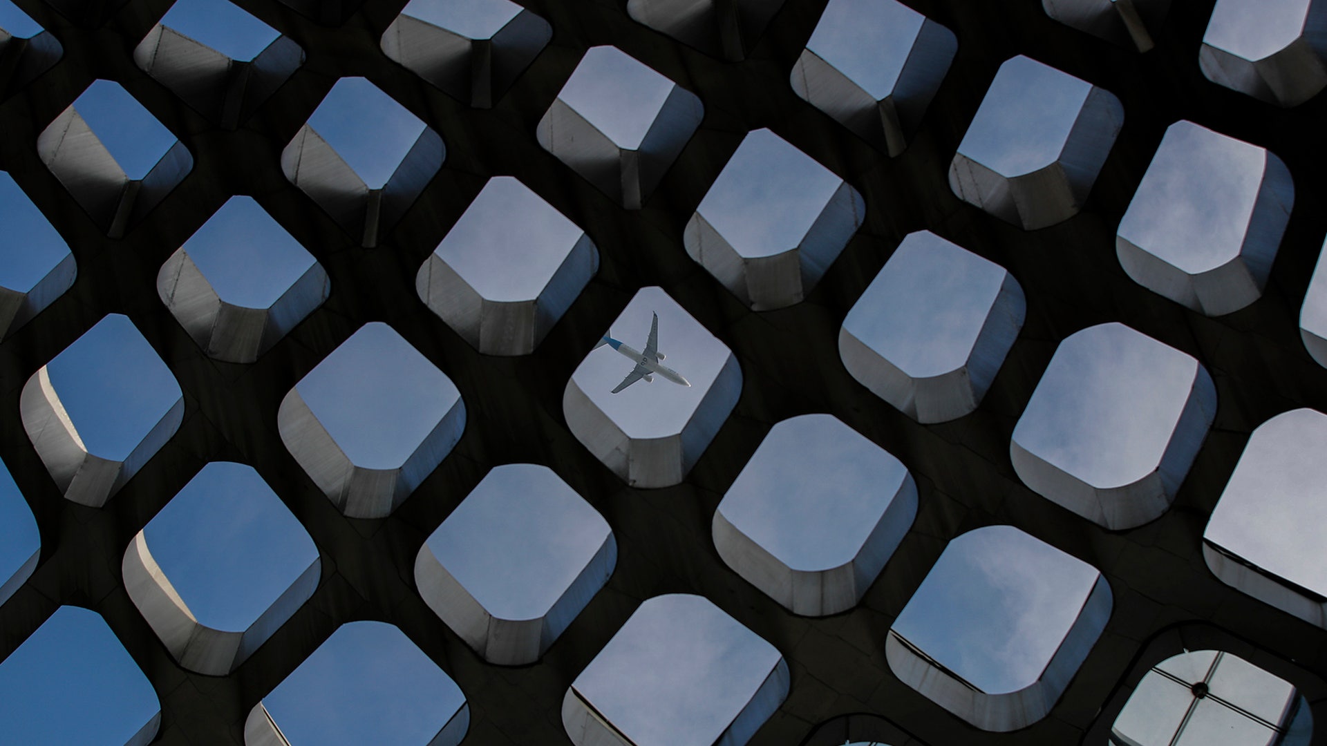 A passenger airliner flies past the Shenzhen Bay Sports Center in Shenzhen, China, Oct. 31, 2019. 