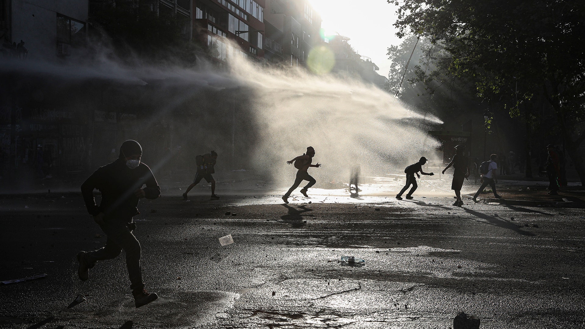 Anti-government protesters run amid the spray of a police water cannon during demonstrations against economic inequality in Santiago, Chile, Oct. 30, 2019. 