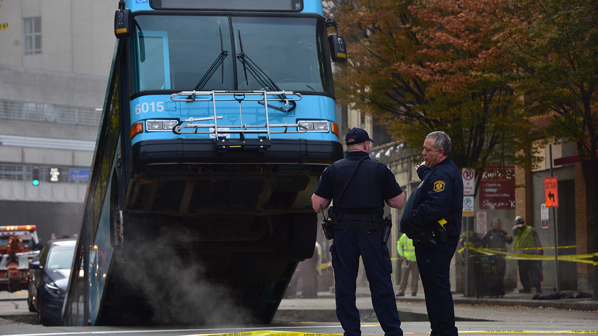 Pittsburgh police officers stand near a Port Authority bus that fell into a sinkhole in Pittsburgh, Oct. 28, 2019. 