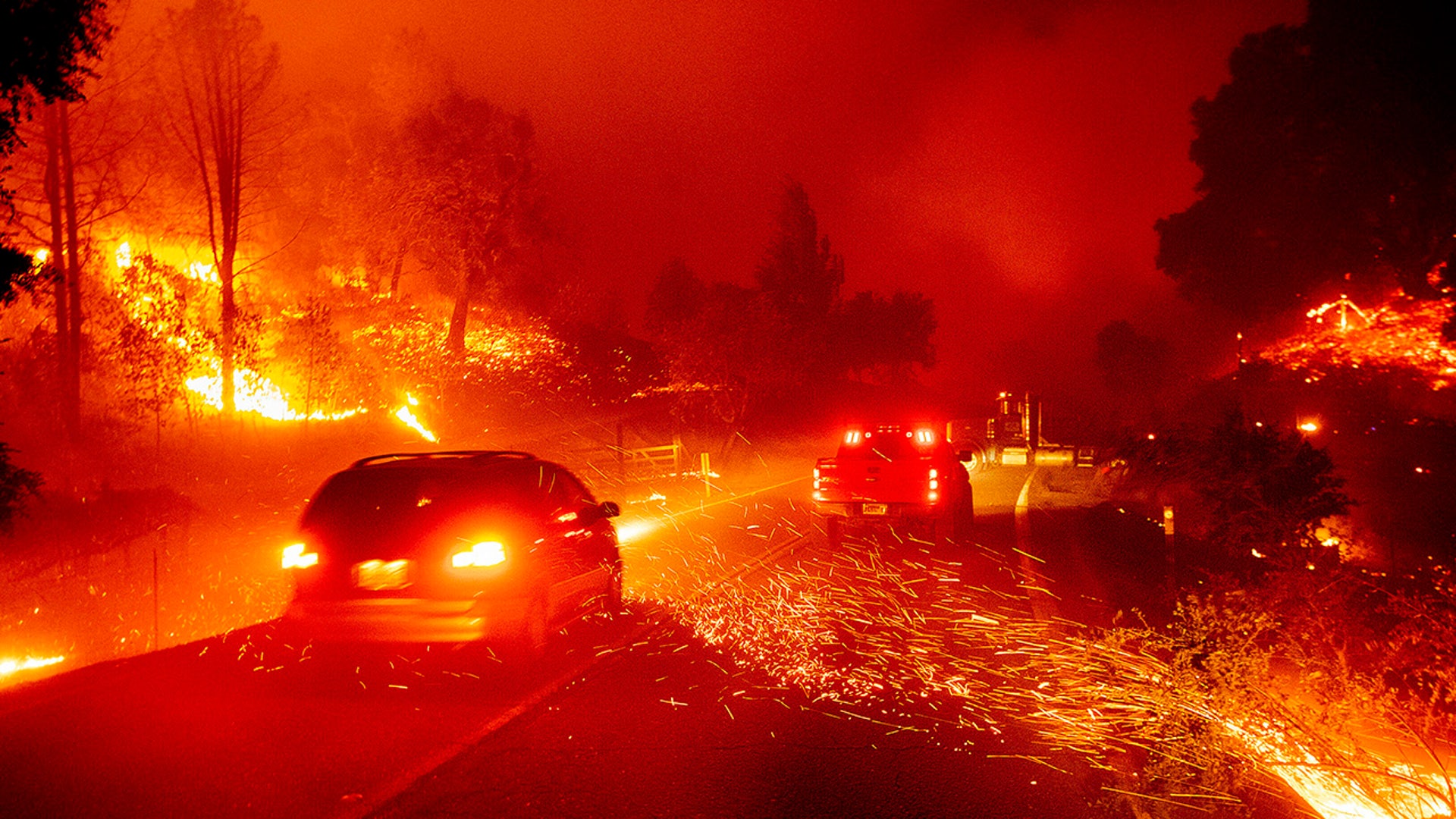 Embers fly across a roadway as the Kincade Fire burns through the Jimtown community of Sonoma County, Calif., on Thursday, Oct. 24, 2019. (AP Photo/Noah Berger)