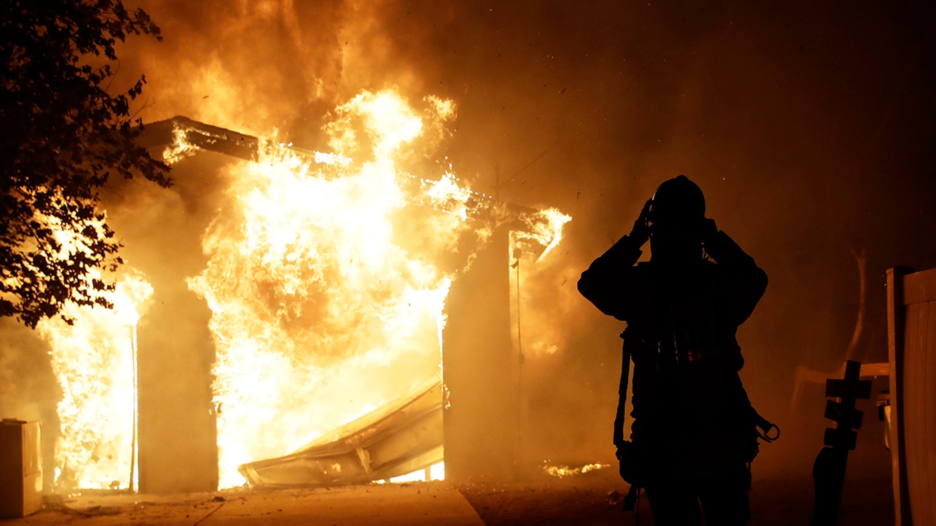 A firefighter prepares to fight a wildfire as it overtakes a home Thursday, Oct. 24, 2019, in Santa Clarita, Calif. The flames are fed by dry winds that are predicted to strengthen across the region. (AP Photo/Marcio Jose Sanchez)