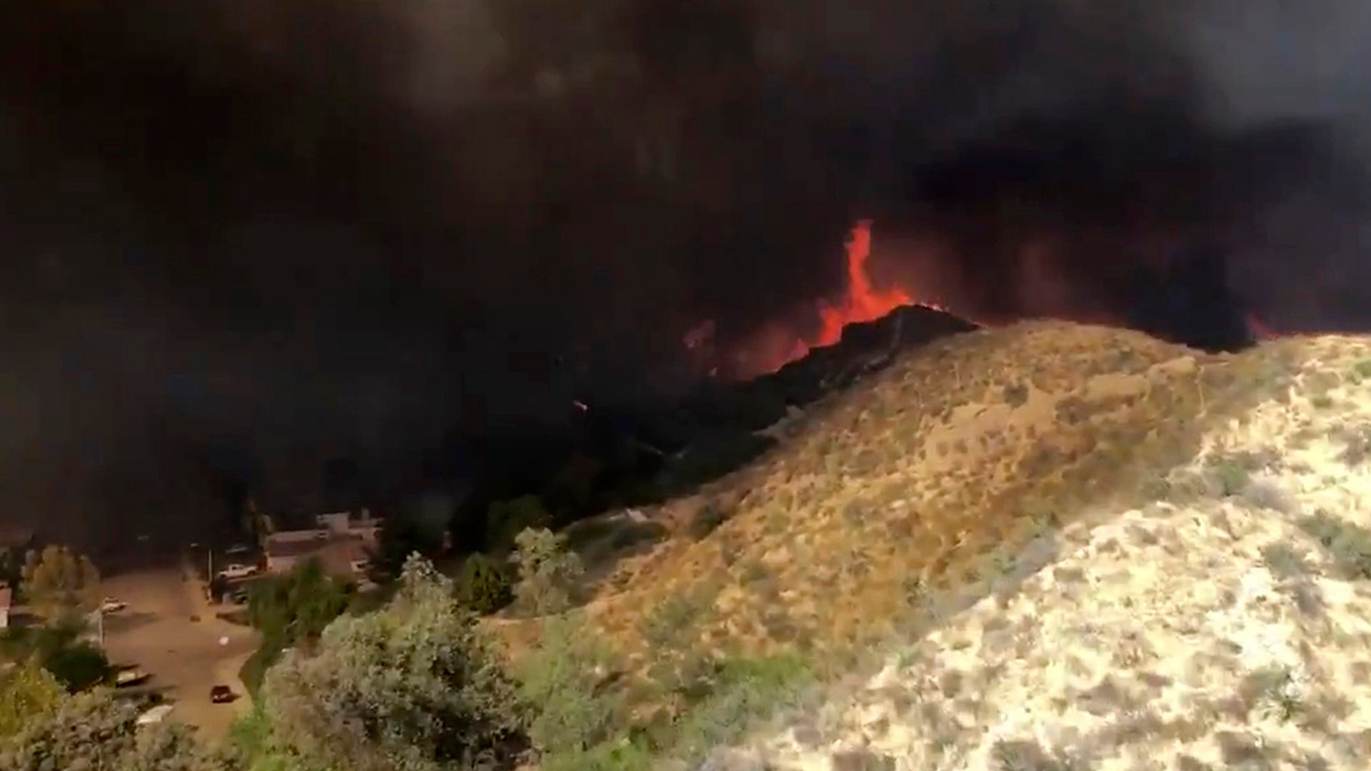 This image taken from aerial video released by Los Angeles County Fire Department Air Operations Section @LACoFireAirOps, shows a view from a Firehawk helicopter battling a wildfire, Thursday, Oct. 24, 2019, in Santa Clarita, Calif. Authorities say at least 40,000 residents have been ordered to evacuate as wind-driven fires rage near neighborhoods north of Los Angeles. (Los Angeles County Fire Department Air Operations Section @LACoFireAirOps via AP)