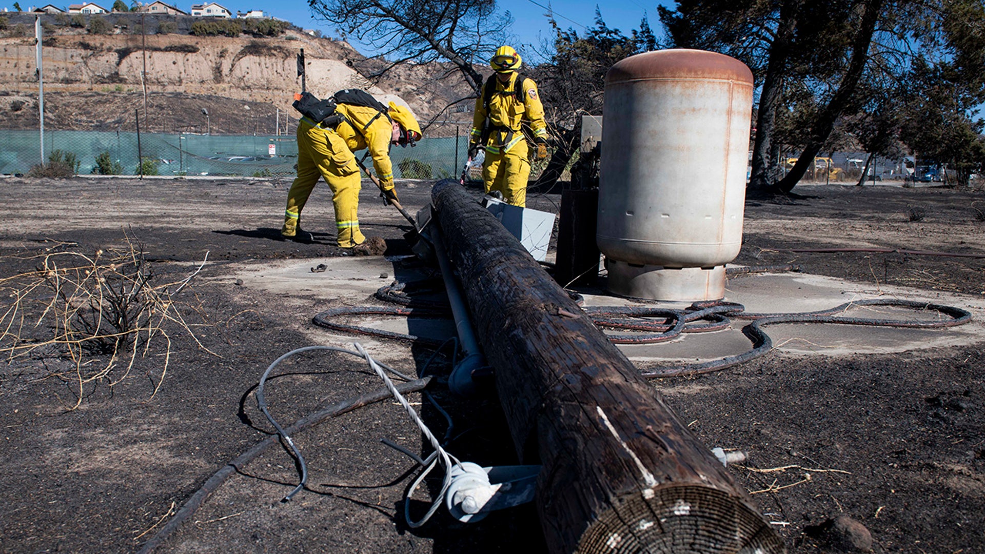 Firefighters with Cal Fire examine a burned down low voltage power pole during the Tick Fire, Thursday, Oct. 25, 2019, in Santa Clarita, Calif. An estimated 50,000 people were under evacuation orders in the Santa Clarita area north of Los Angeles as hot, dry Santa Ana winds howling at up to 50 mph (80 kph) drove the flames into neighborhoods (AP Photo/ Christian Monterrosa)