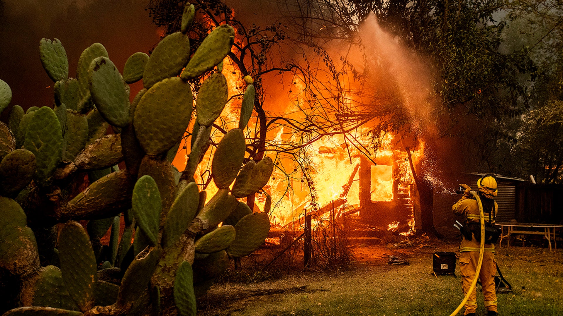 A firefighter sprays water on a burning home as the Kincade Fire burns through the Jimtown community of unincorporated Sonoma County, Calif., on Thursday, Oct. 24, 2019. (AP Photo/Noah Berger)