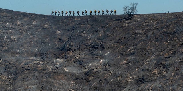 Fire crews walk along a blackened ridge as they battle the Getty fire Monday, Oct. 28, 2019, in Los Angeles. (Associated Press)