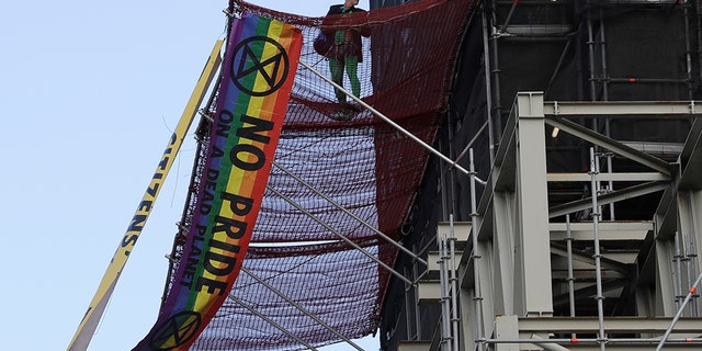 A climate protester demonstrates with banners on the scaffolding covering the Elizabeth Tower that houses the Big Ben clock in London, Friday, Oct. 18, 2019.