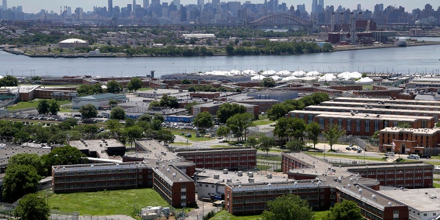 The Rikers Island jail complex, set against the backdrop of the New York City skyline.