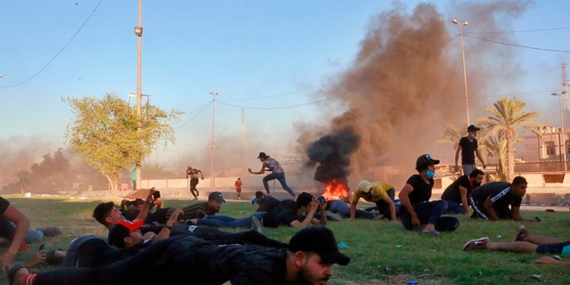 Anti-government protesters taking cover while Iraqi security forces fired during a demonstration in Baghdad this past Friday. (AP Photo/Khalid Mohammed)