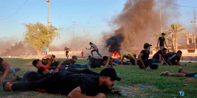 Anti-government protesters take cover while Iraq security forces fire during a demonstration in Baghdad, Iraq, Friday, Oct. 4, 2019. Security forces opened fire directly at hundreds of anti-government demonstrators in central Baghdad, killing several protesters and injuring dozens, hours after Iraq's top Shiite cleric warned both sides to end four days of violence "before it's too late." (AP Photo/Khalid Mohammed)