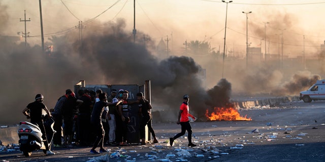 Anti-government protesters set fires and close a street during a demonstration in central Baghdad on Friday. Security forces opened fire, killing some protesters and injuring dozens, hours after Iraq's top Shiite cleric warned both sides to end four days of violence "before it's too late." (AP Photo/Khalid Mohammed)