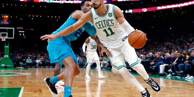 Boston Celtics' Enes Kanter (11) drives past Charlotte Hornets' PJ Washington (25) during the first half of a preseason NBA basketball game in Boston.