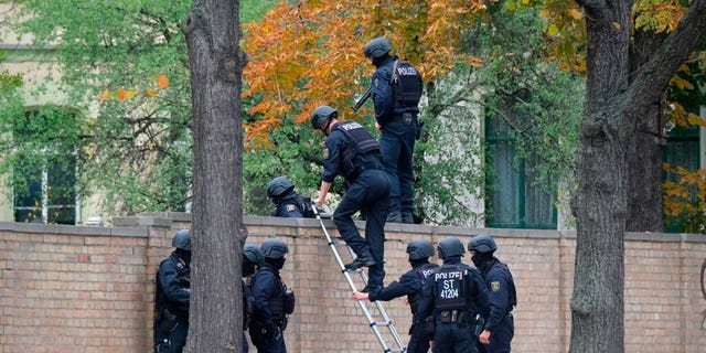 Police officers pictured here crossing a wall at a crime scene in Halle, Germany on Wednesday.