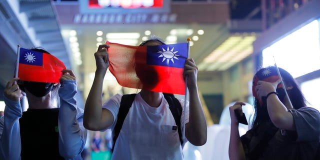 People hold Taiwanese flags as they join others at a rally to mark Taiwan's National Day, in the Tsim Sha Tsui district in Hong Kong, Thursday, Oct. 10, 2019.
