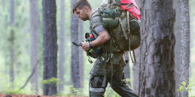 A soldier from the U.S. Army John F. Kennedy Special Warfare Center and School checks a compass while completing a land navigation course during Special Forces Assessment and Selection near Hoffman, N.C., May 7, 2019. (Ken Kassens/U.S. Army via AP)